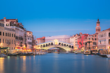 The Rialto Bridge illuminated at night at twilight over the Grand Canal in Venice, Italy.