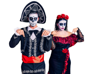 Young couple wearing mexican day of the dead costume over background pointing down looking sad and upset, indicating direction with fingers, unhappy and depressed.