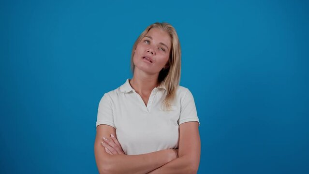 Woman in impatient, waiting for something feeling sorrow, regret, drama, failure, problems on blue background. An upset girl stands in front of the camera with her arms folded across her chest