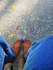 after the festival, confetti on the asphalt underfoot, view down, boots and jeans, holiday, fiesta,...