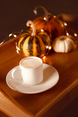 cup of pumpkin coffee on wooden tray with small decorative pumpkins. winter holiday mood