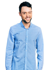 Hispanic man with beard wearing casual business shirt winking looking at the camera with sexy expression, cheerful and happy face. - obrazy, fototapety, plakaty