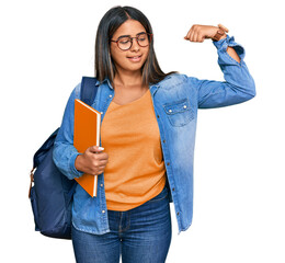 Young latin girl wearing student backpack and holding books strong person showing arm muscle, confident and proud of power