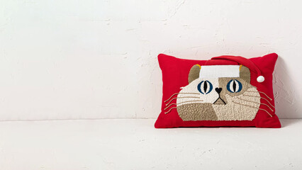 Cotton embroidered cat pillow on copy-space background.