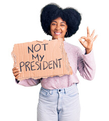 Young african american girl holding not my president protest banner doing ok sign with fingers,...