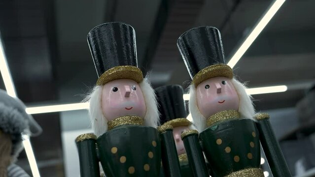 Nutcracker wooden dolls dressed in green costumes with golden details, standing on the modern buildings ceiling background with linear lights. Panning shot of Christmas Nutcracker toy dolls.