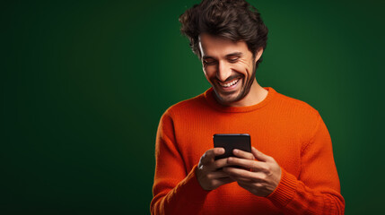 Fototapeta premium Young man is using a smartphone against green background.