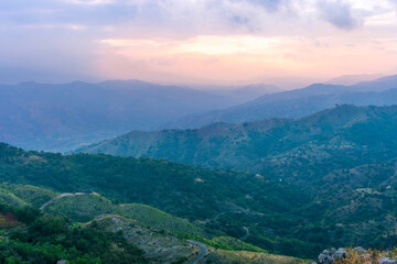 highland mountain landscape of beautiful sunset or sunrise with nice mountain peaks and slopes, green and golden hills and majestic cloudy sky on background