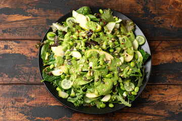 Super green salad with spinach, broccoli, apples, cucumber and edamame beans served with avocado,...