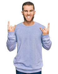 Fototapeta premium Young caucasian man wearing casual clothes shouting with crazy expression doing rock symbol with hands up. music star. heavy concept.