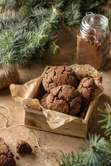Homemade christmas chocolate cookies in wooden box on brown festive background with fir tree branches. Christmas holiday desserts, xmas gifts