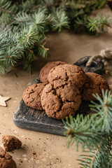 Homemade christmas chocolate cookies on wooden board and coffee on brown festive background with fir tree branches. Christmas holiday desserts