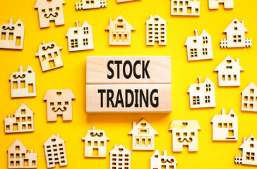 Stock trading symbol. Concept words Stock trading on beautiful wooden blocks. Beautiful yellow table yellow background. House model. Business stock trading concept. Copy space.