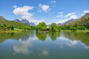 Fototapeta na wymiar Postcard Cafe in the middle of the lake at Stark-Conde Wines and the Jonkershoek Mountains range in the background with Stellenbosch Mountain peak touching the clouds, Cape Town, South Africa