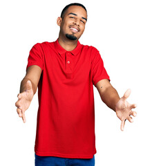 Young african american man wearing casual polo looking at the camera smiling with open arms for...