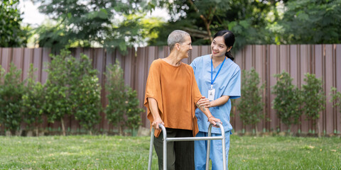 Nurse or caregiver help elderly walk by using walker in garden