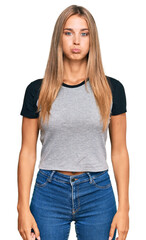 Obraz premium Young blonde woman wearing casual clothes puffing cheeks with funny face. mouth inflated with air, crazy expression.