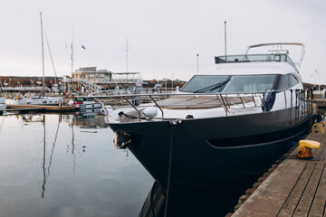 Fototapeta premium Luxury yacht anchored in the port. Ocean Coast pier. High class lifestyle. Sea transport. Journey concept. Yachting sport. Expensive yachts at the pier.