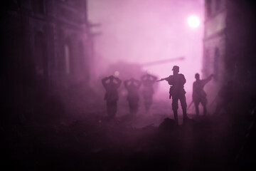 Military silhouettes fighting scene on war fog sky background. A German soldiers raised arms to surrender. Plastic toy soldiers with guns taking prisoner the enemy soldier.