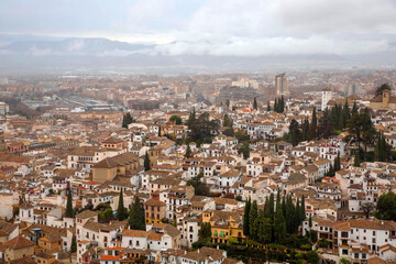 Fototapeta na wymiar View of the city of Granada from the top of the hill where is the Alhambra Palace. City scenery against a cloud sky. Granada, Spain.