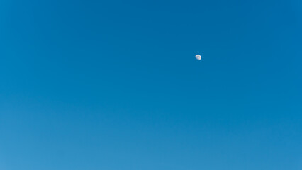 Half bright moon on blue sky background.