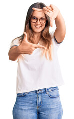 Fototapeta premium Beautiful caucasian woman wearing casual clothes and glasses celebrating achievement with happy smile and winner expression with raised hand