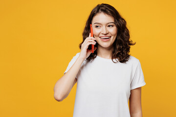 Young woman she wear white blank t-shirt casual clothes talk speak on mobile cell phone conducting...