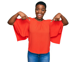 Young african american woman wearing casual clothes looking confident with smile on face, pointing...