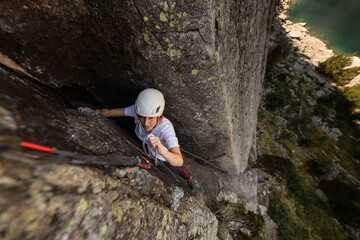 Obraz premium Person climbing in high mountains with yellow jacket rope and helmet in nature, confidence and risk, safety