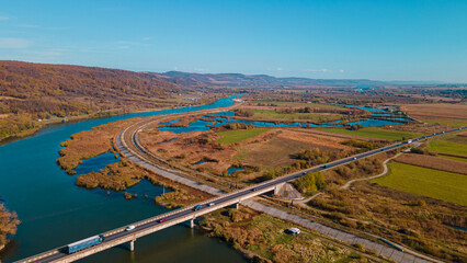 Road bridge over Olt river, autumn colours in Romania | drone view