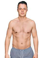 Fototapeta premium Handsome young man wearing swimwear shirtless relaxed with serious expression on face. simple and natural looking at the camera.