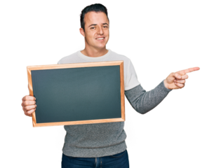 Handsome young man holding blackboard smiling happy pointing with hand and finger to the side