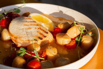 Fried Portuguese scallops in white wine sauce with lemon, tomatoes and toast. Seafood