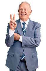 Senior handsome grey-haired man wearing elegant suit smiling with happy face winking at the camera doing victory sign. number two.