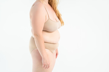 Tummy tuck, flabby skin on a fat belly, plastic surgery and liposuction concept on gray background