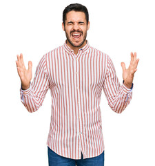 Young hispanic man wearing business shirt celebrating mad and crazy for success with arms raised...