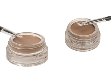 A brow pomade in blonde shade with brush isolated on a white background.