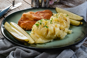 Pork chop served with mashed potatoes and pickled cucumber.