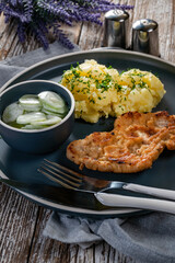 Pork chop served with mashed potatoes and cucumber salad.