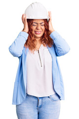 Young latin woman wearing architect hardhat suffering from headache desperate and stressed because pain and migraine. hands on head.