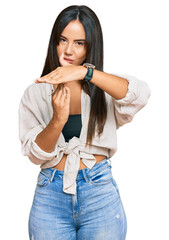 Young beautiful hispanic girl wearing casual clothes doing time out gesture with hands, frustrated...