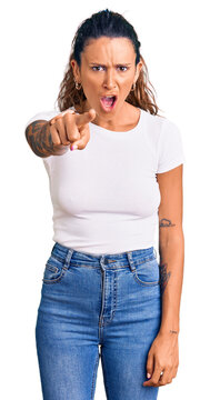 Young hispanic woman with tattoo wearing casual white tshirt pointing displeased and frustrated to the camera, angry and furious with you