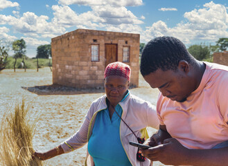 african village, old woman opening in front of the house with an ngo worker on the phone