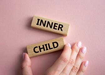 Inner Child symbol. Wooden blocks with words Inner Child. Beautiful pink background. Businessman hand. Business and Inner Child concept. Copy space.