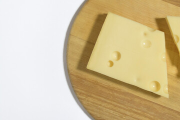 Emmental cheese on a round wooden kitchen board. Cheese with holes. Close-up
