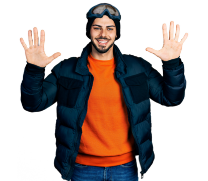 Young hispanic man with beard wearing snow wear and sky glasses showing and pointing up with fingers number ten while smiling confident and happy.
