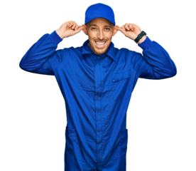Bald man with beard wearing builder jumpsuit uniform smiling pulling ears with fingers, funny gesture. audition problem