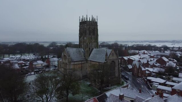 Drone shot. Snow winter scene. Church of England. Parish church in English countryside. Christian church worship UK. 