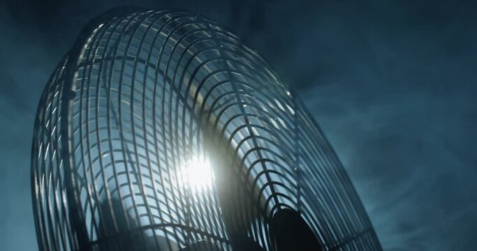 Fan blades rotate in rays of light and fog.