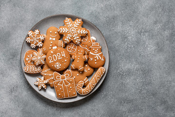 Set of gingerbread cookies in a plate, gray concrete background. New Year 2024. Top view, flat lay,...